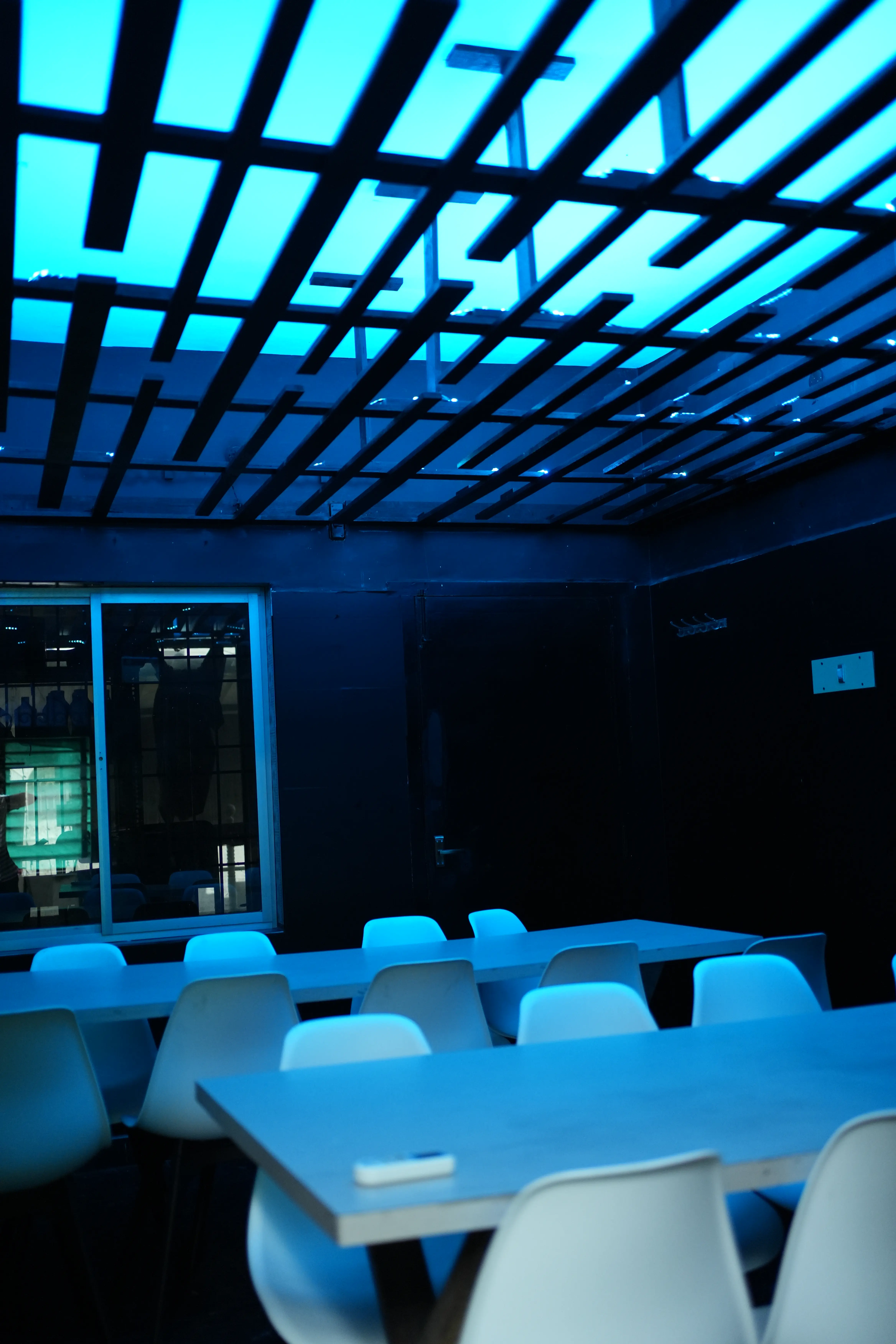 Blue-lit function hall with rows of white chairs and long tables ready for a party booking