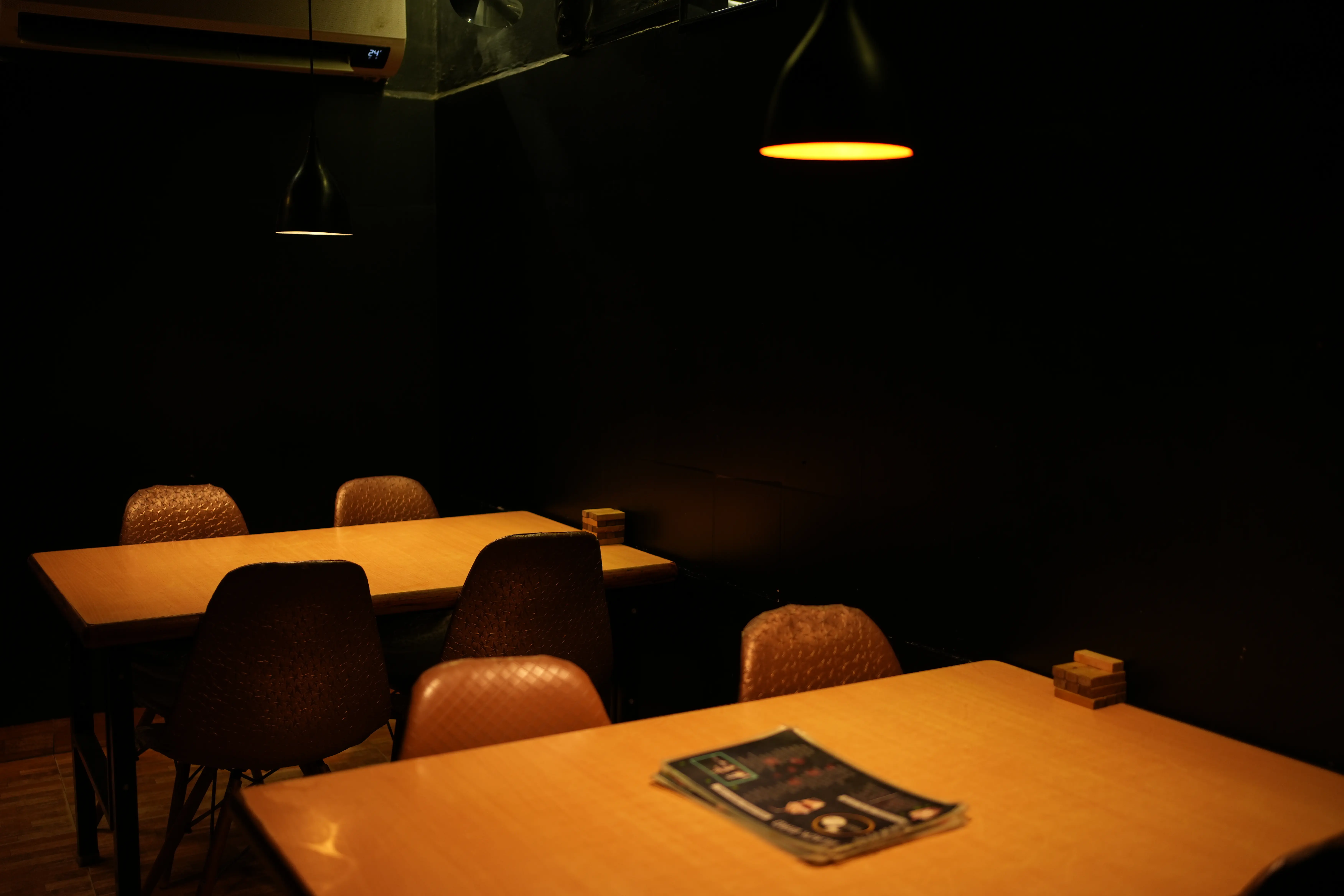 Warmly lit dining area with wooden tables, brown chairs and a menu card waiting on the table