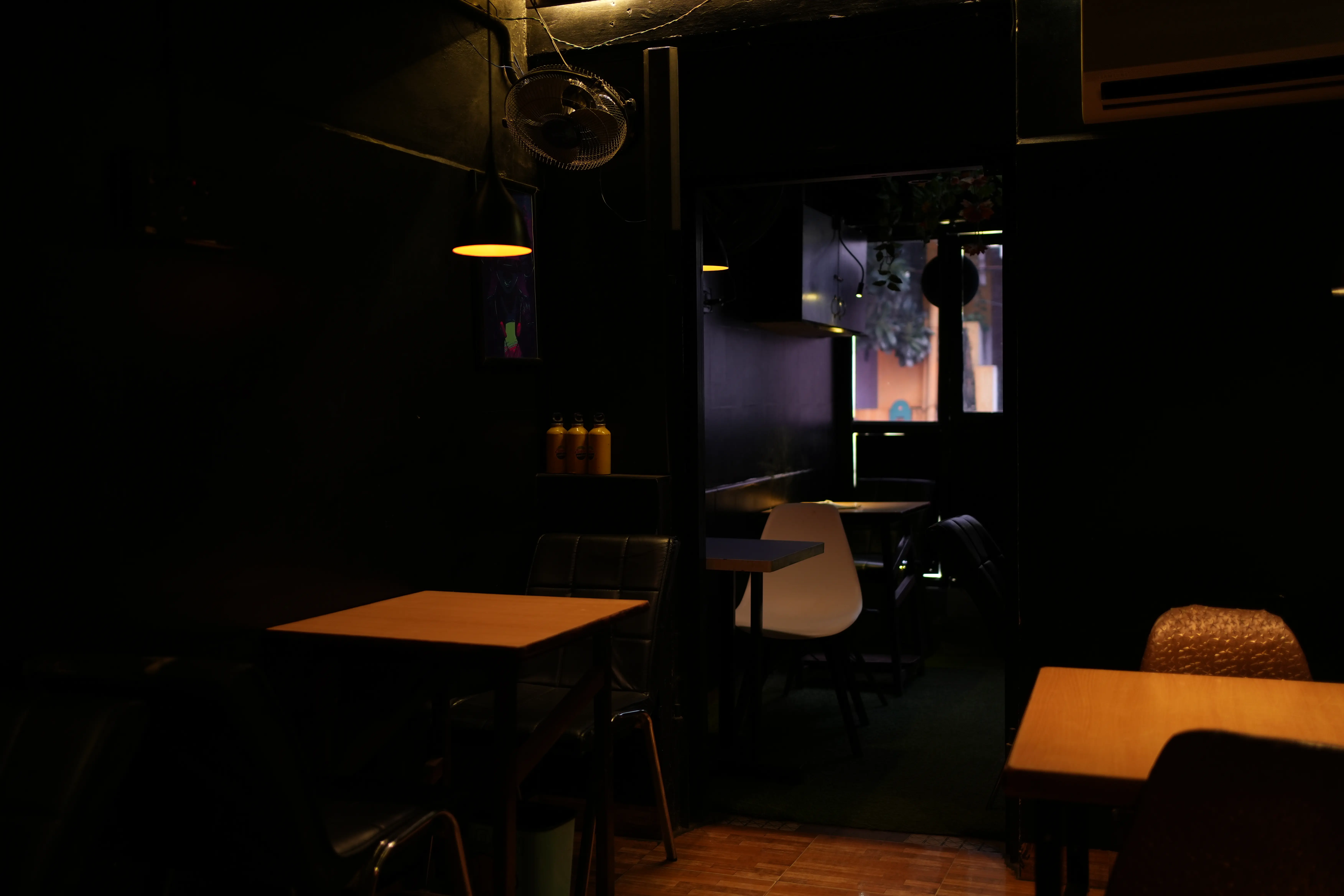 The dining room in the evening, pendant lights hanging over orange-topped tables