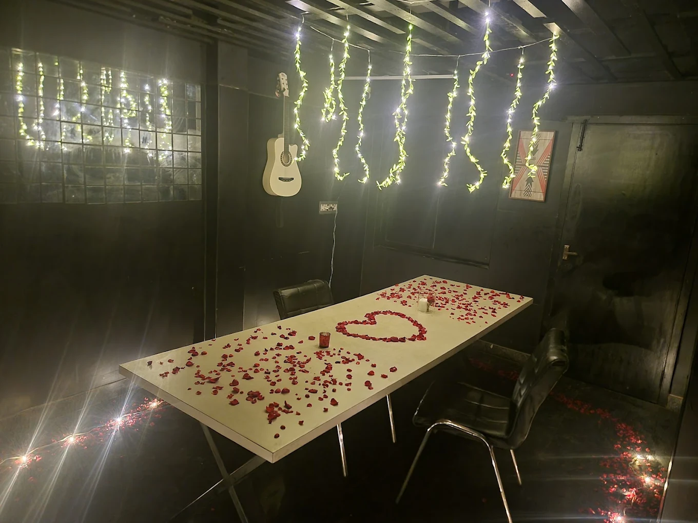 A private table laid out with rose petals in a heart and fairy lights for a celebration