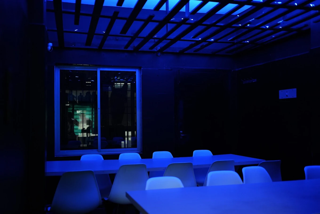 Upstairs hall lit in blue, with long tables and white chairs set up for a large group