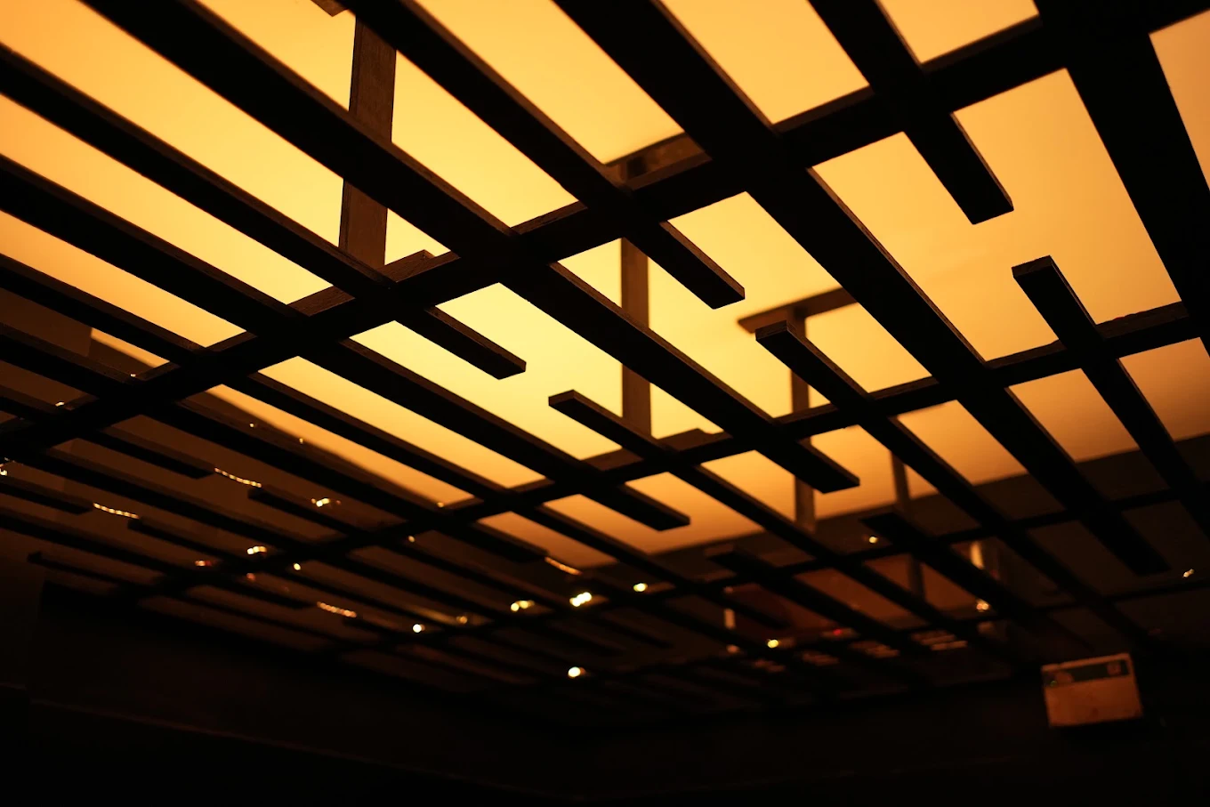 The amber backlit ceiling grid that gives the dining room its warm evening glow